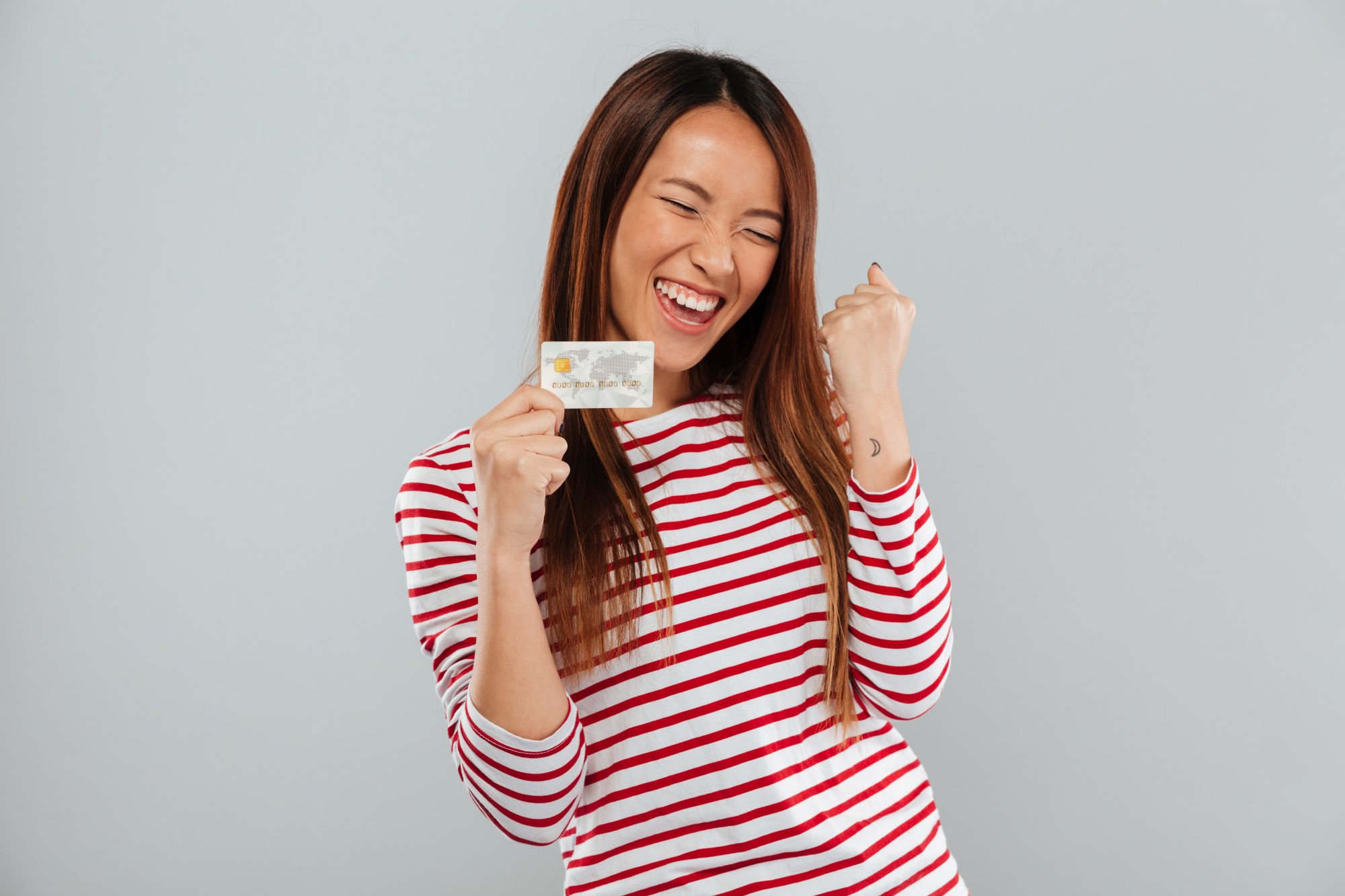 happy asian woman celebrates with credit card